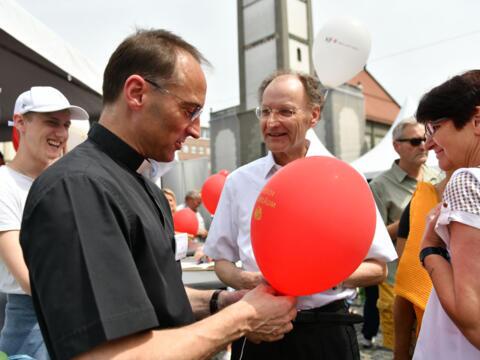 Beim großen Jubiläumsfest auf dem Augsburger Rathausplatz ließ auch Stadtpfarrer Christoph Hänsler (vorne) eine Wunschkarte per Luftballon zum Himmel steigen. In der Bildmitte: Generalvikar Monsignore Wolfgang Hacker. (Foto: Rösch/pba)